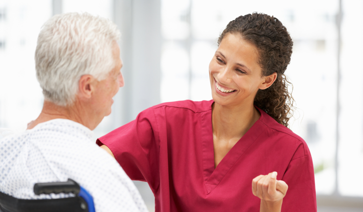 Female nurse smiling at male patient in a wheelchair