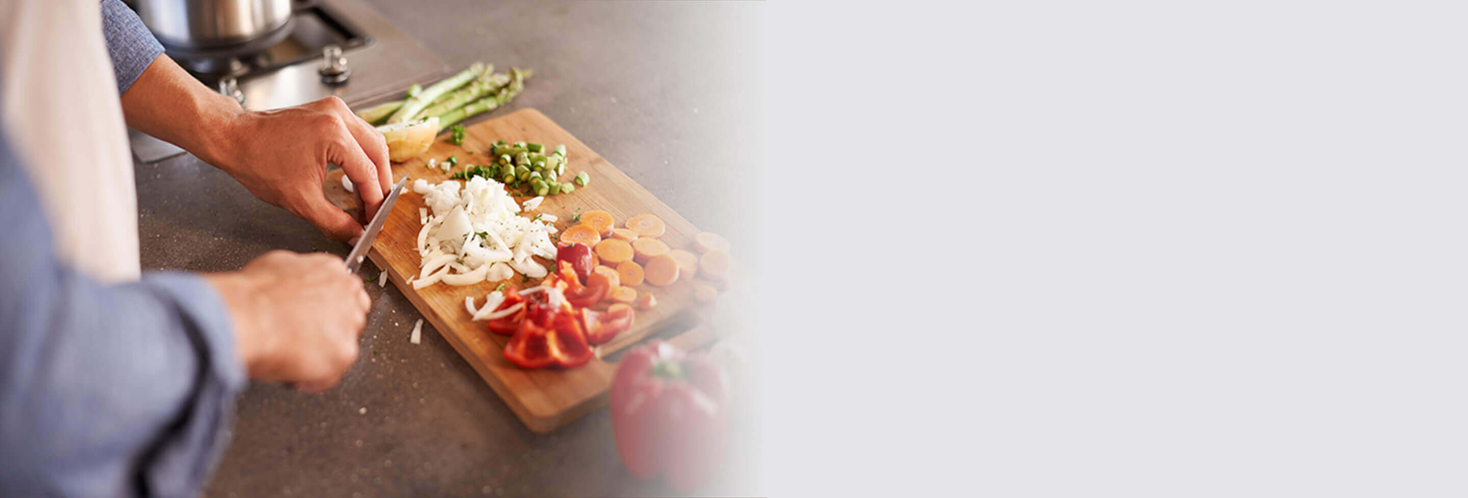 person cutting vegetables with a knife on a cutting board