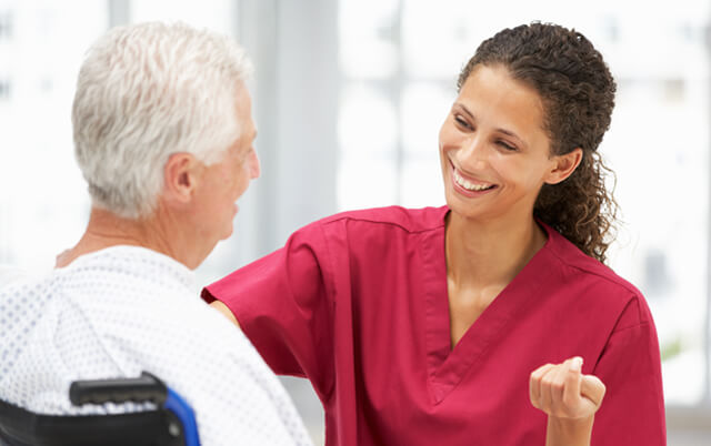 Female nurse with senior male patient in wheelchair smiling